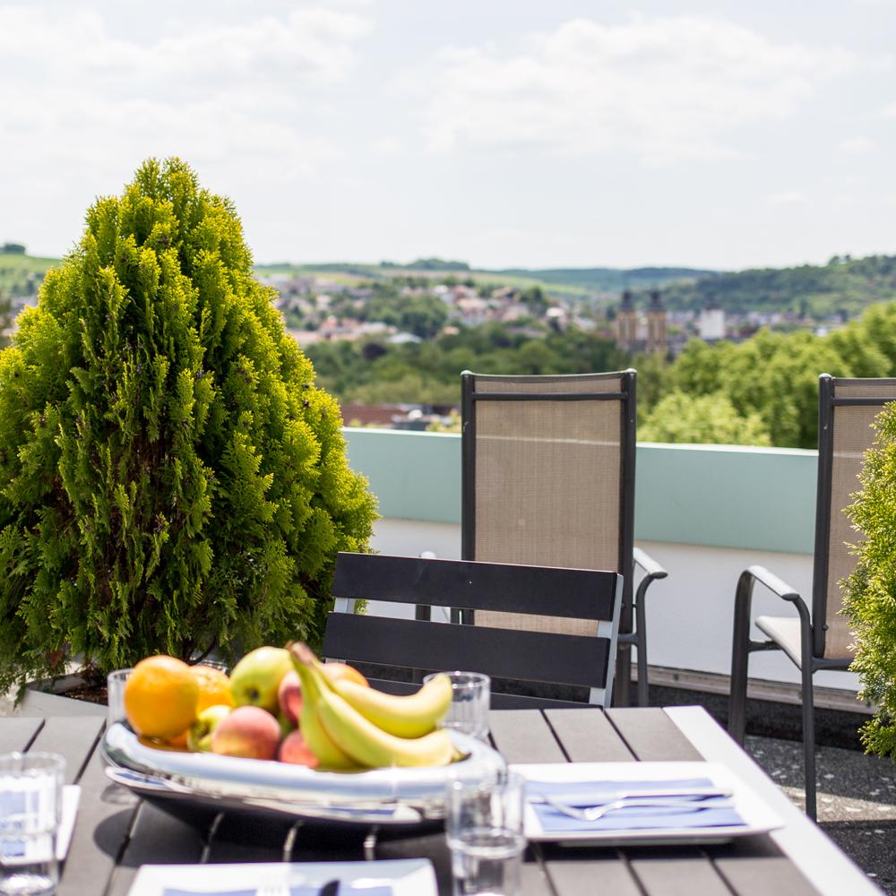 Gedeckter Gartentisch mit Stühlen auf einem Balkon