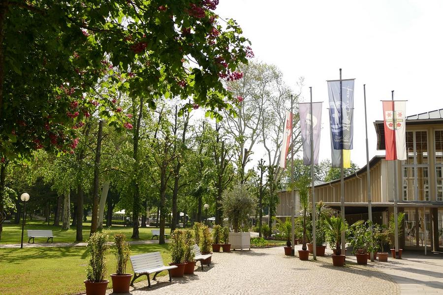 Außenbereich des Kursaals mit Park im Hintergrund und Bänken