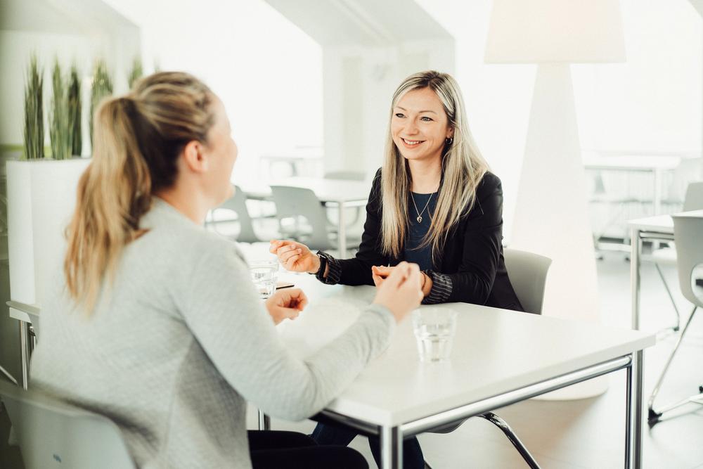 Zwei junge Frauen sitzen sich gegenüber und sprechen miteinander