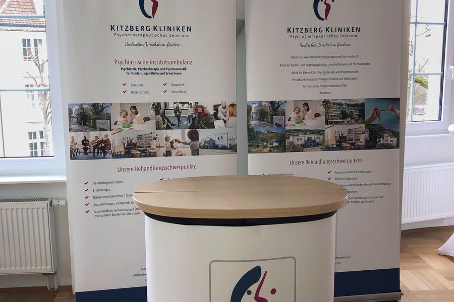 Pult mit Kitzberg-Logo darauf und zwei Aufsteller mit Logo und Bild als Hintergrund