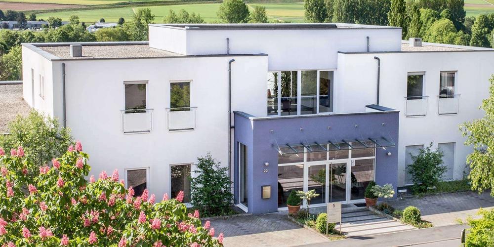 Drohnenaufnahme vom Psychotherapeutischen Zentrum, ein weißes Gebäude mit blauem Eingangsbereich