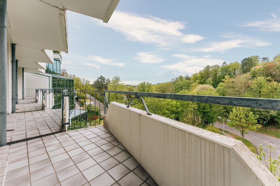 Balkon mit hellem Fliesenboden und Blick auf Wald