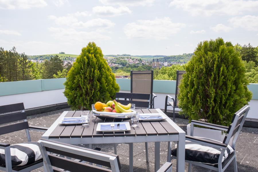 Gedeckter Gartentisch mit Stühlen auf einem Balkon