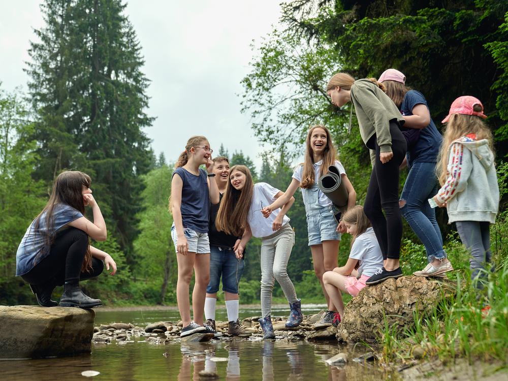 Kinder und Jugendliche versammelt an einem Flussufer