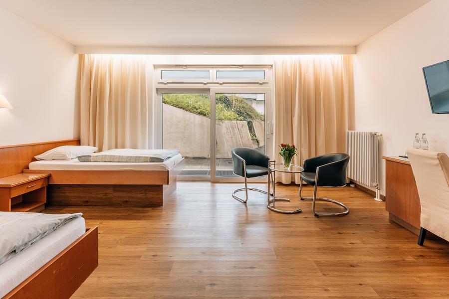 Großes Zimmer mit zwei Einzelbetten, zwei Stühlen und großer Balkontür